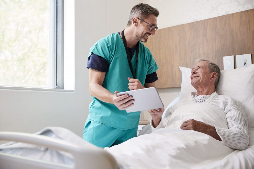 Surgeon With Digital Tablet Visiting Senior Male Patient