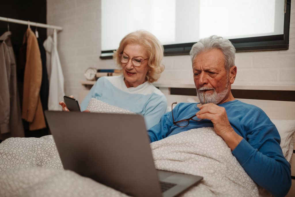 Elderly couple checking their mobile & laptop.