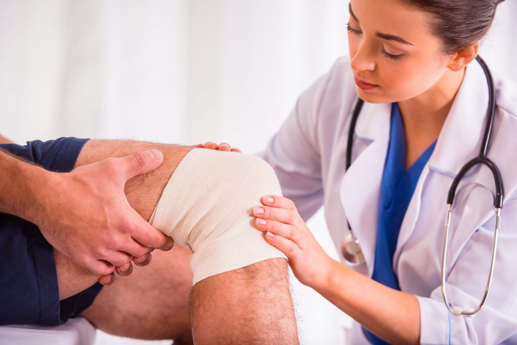 Nurse Applying Compression Wraps on patient's wounded leg