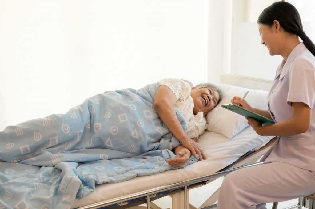 Smiling Female Nurse Talking with Patient and Checking Reports
